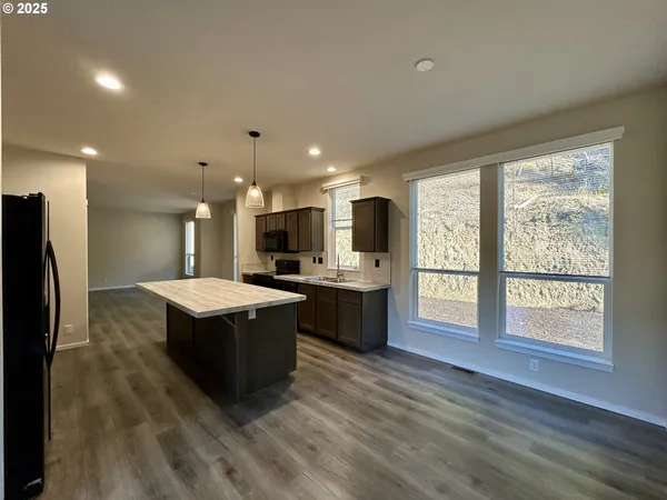 a kitchen with kitchen island a counter top space a sink stainless steel appliances and cabinets
