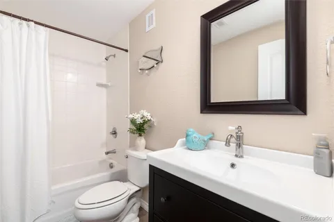 a bathroom with a bathtub shower sink vanity mirror and toilet