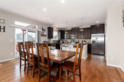 a kitchen with stainless steel appliances granite countertop a dining table chairs refrigerator and cabinets