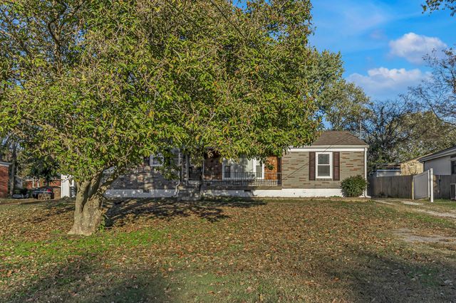 a front view of a house with a yard tree and outdoor seating