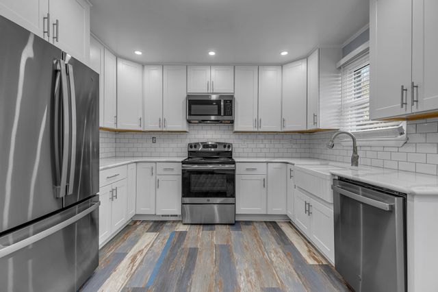 a kitchen with cabinets stainless steel appliances and a window