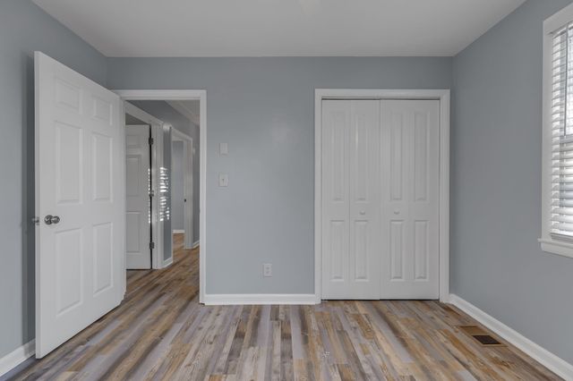 a view of an empty room with closet and a window