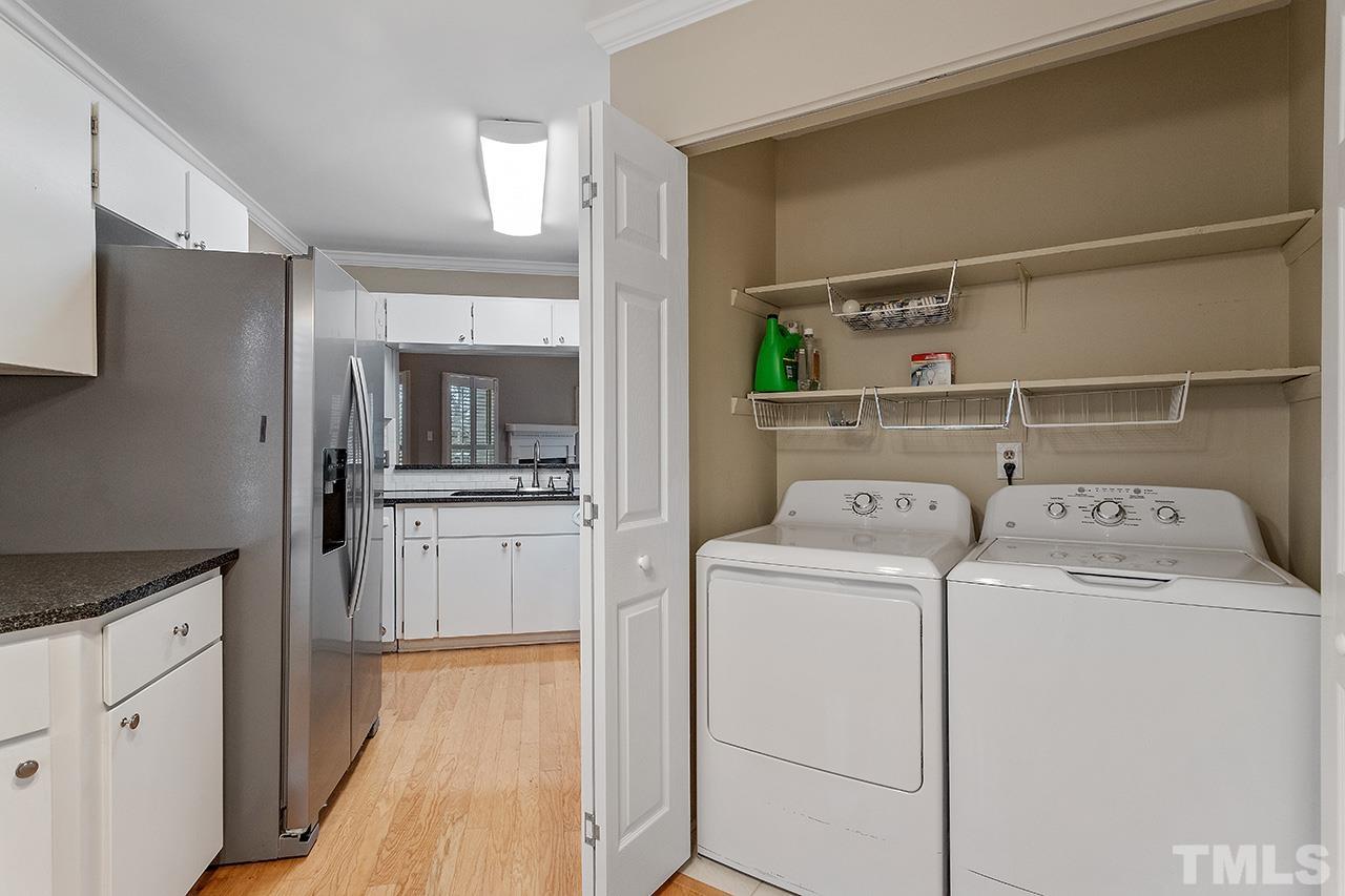 5701 Grasmere Court Raleigh, NC 27609 - Photo 13 of 34 a view of washer and dryer with kitchen in the background