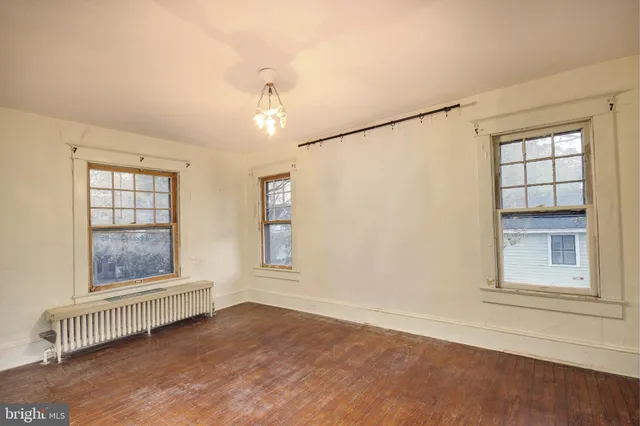 an empty room with wooden floor cabinet and windows