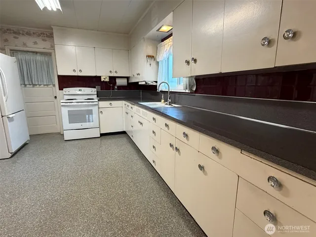 a kitchen with granite countertop white cabinets and white appliances