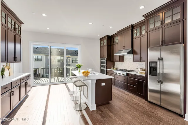 a kitchen with stainless steel appliances granite countertop a refrigerator a stove and a wooden floors