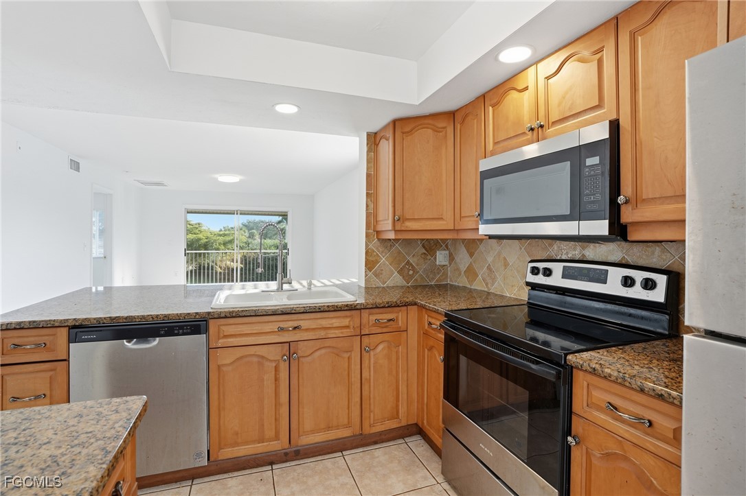 240 Pebble Beach Boulevard, Unit 712 Naples, FL 34113 - Photo 4 of 22 a kitchen with stainless steel appliances granite countertop a stove microwave and sink