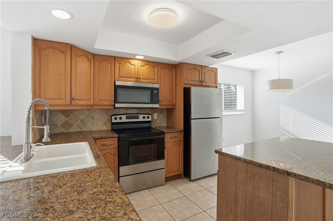 240 Pebble Beach Boulevard, Unit 712 Naples, FL 34113 - Photo 5 of 22 a kitchen with granite countertop a refrigerator and a sink