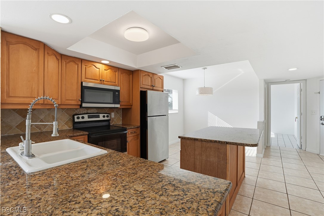 240 Pebble Beach Boulevard, Unit 712 Naples, FL 34113 - Photo 6 of 22 a kitchen with granite countertop a refrigerator and a sink