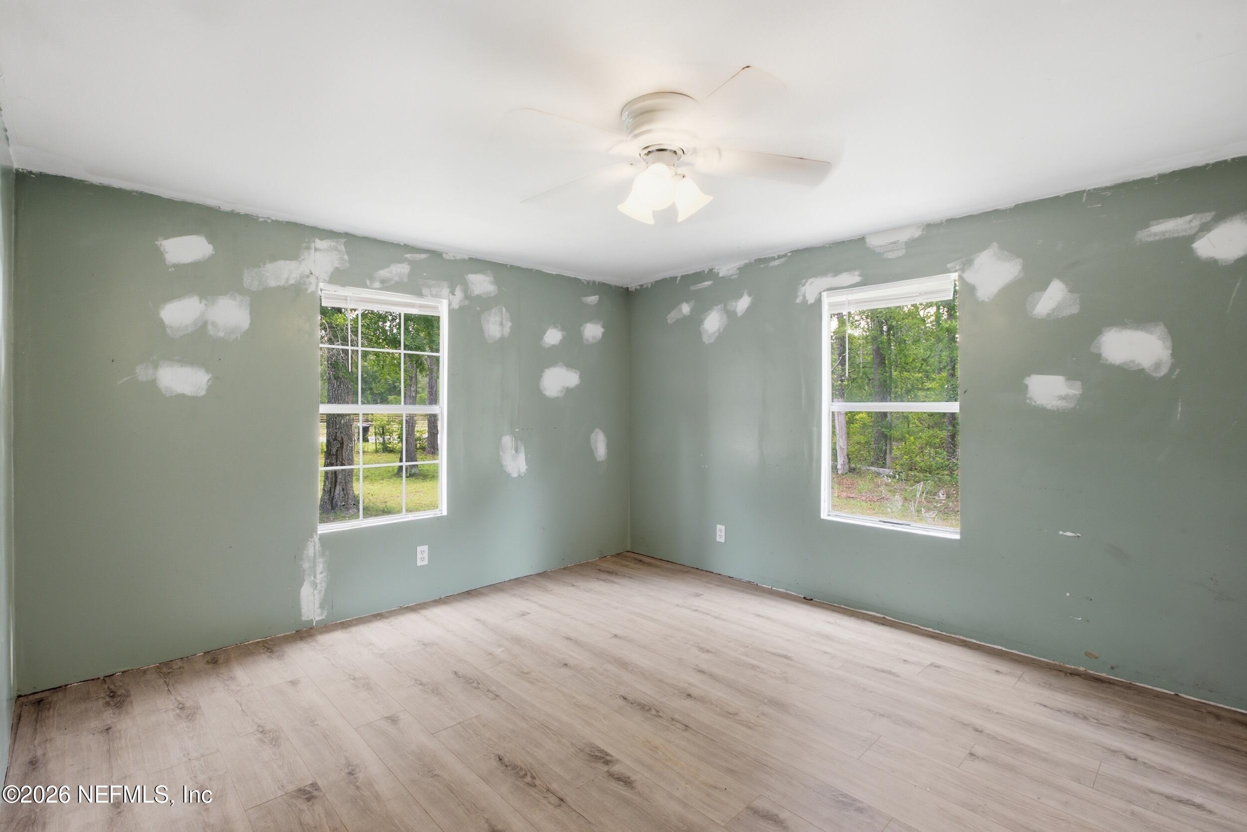 5667 Long Branch Cemetery Road Jacksonville, FL 32234 - Photo 17 of 24 an empty room with windows and chandelier fan