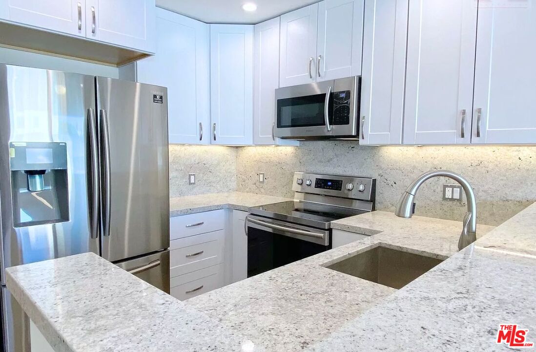 a kitchen with stainless steel appliances kitchen island granite countertop a refrigerator stove and sink