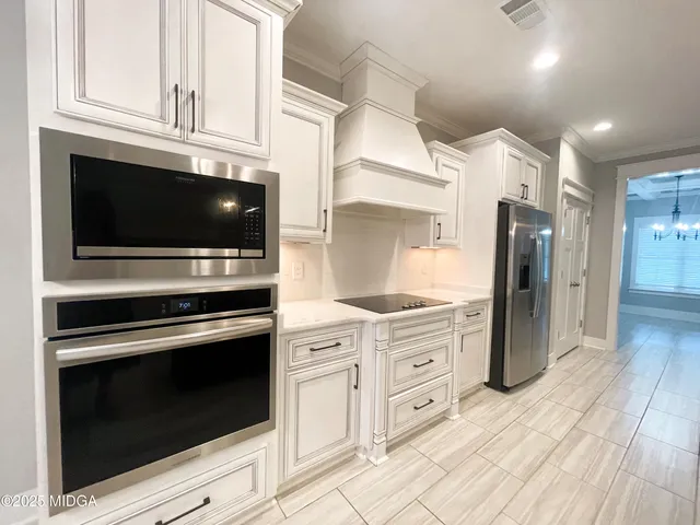 a kitchen with stainless steel appliances white cabinets and a stove top oven