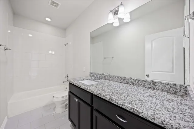 a bathroom with a granite countertop sink a toilet and shower