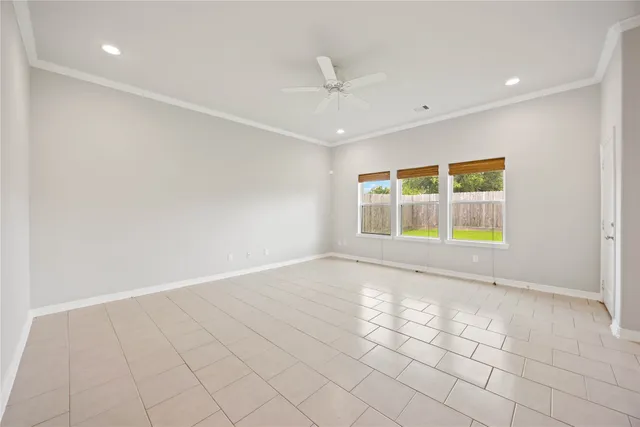 an empty room with windows and ceiling fan