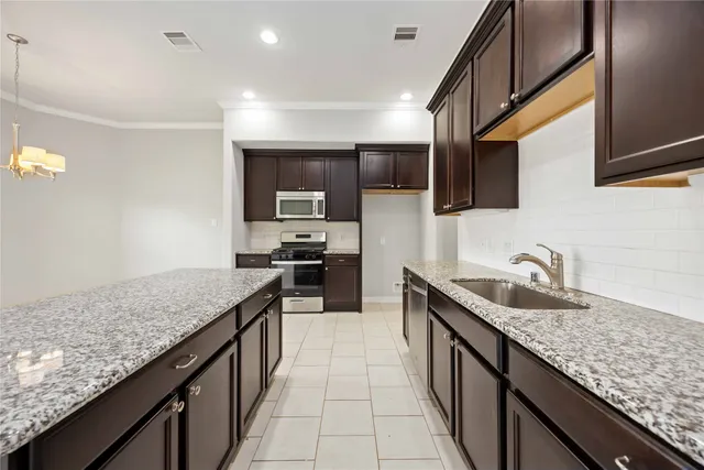 a kitchen with granite countertop stainless steel appliances a sink stove top oven and cabinets