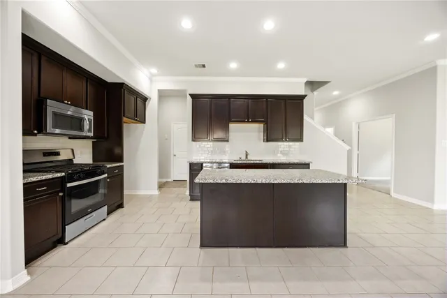 a large kitchen with stainless steel appliances a stove a sink and a microwave