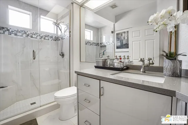 a bathroom with a double vanity sink mirror double shower and a toilet