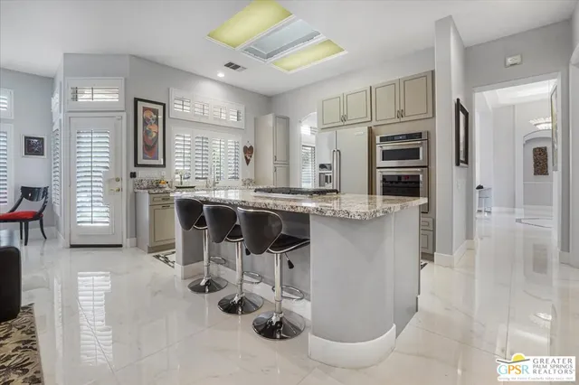 a kitchen with stainless steel appliances kitchen island granite countertop a refrigerator and cabinets