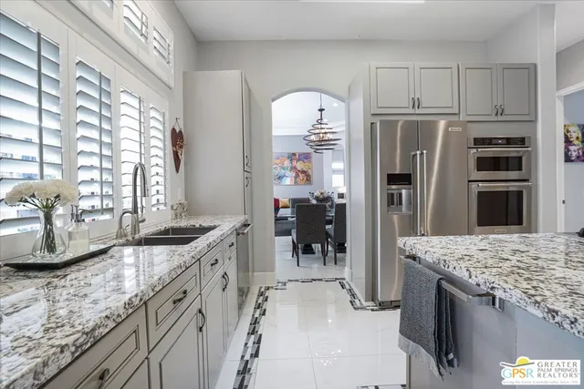 a kitchen with granite countertop a sink a counter top space appliances and cabinets