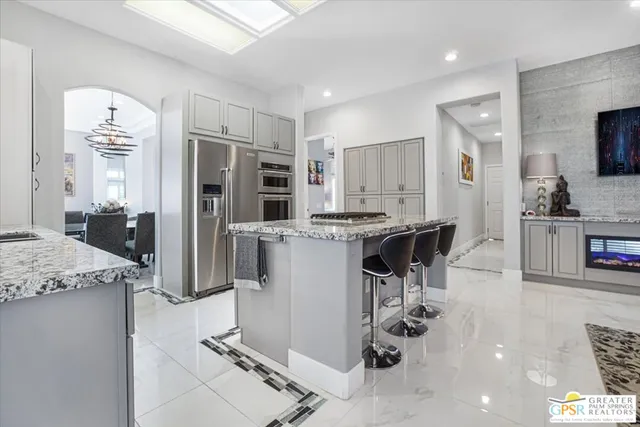 a kitchen with stainless steel appliances kitchen island granite countertop a refrigerator and a stove top oven