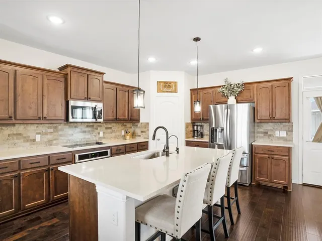 a kitchen with stainless steel appliances granite countertop a kitchen island hardwood floor sink stove and refrigerator