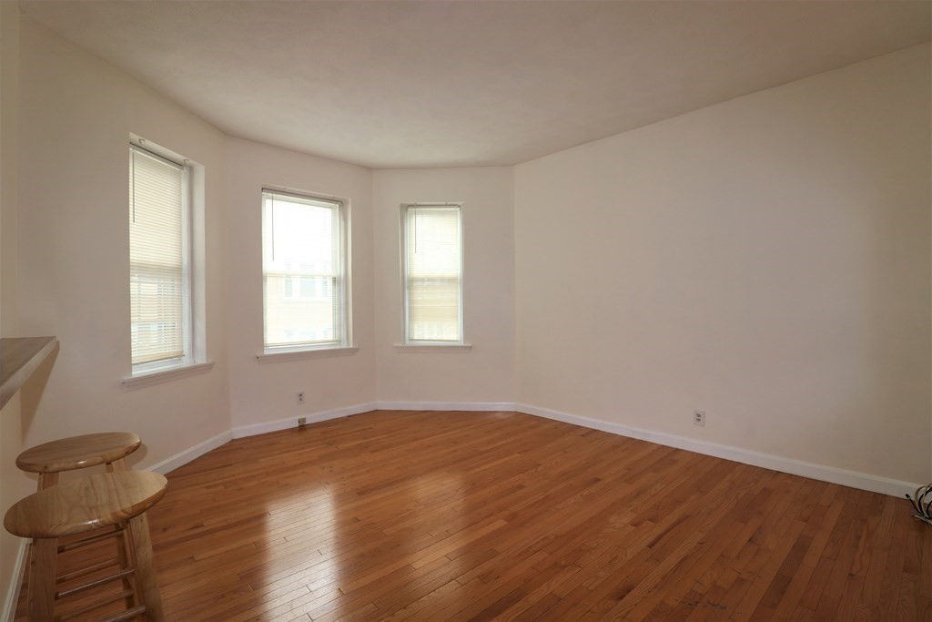 1427 Commonwealth Avenue, Unit 302 Boston, MA 02135 - Photo 5 of 12 an empty room with wooden floor and windows