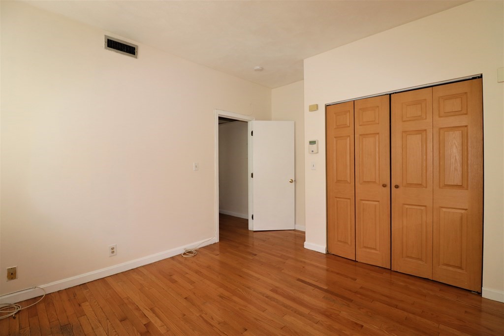 1427 Commonwealth Avenue, Unit 302 Boston, MA 02135 - Photo 7 of 12 an empty room with wooden floor and closet area