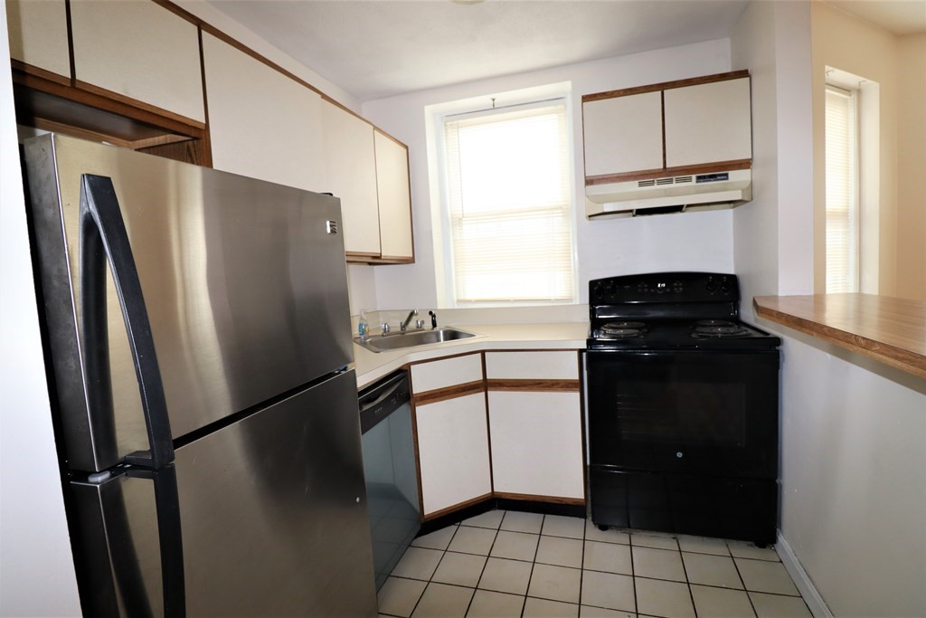 1427 Commonwealth Avenue, Unit 302 Boston, MA 02135 - Photo 9 of 12 a kitchen with a refrigerator stove and cabinets