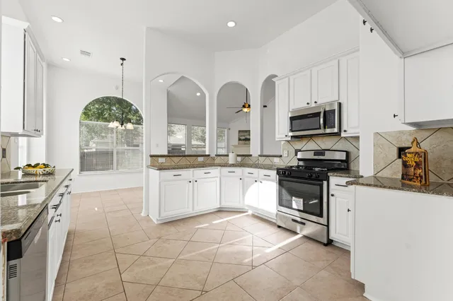 a kitchen with stainless steel appliances granite countertop a stove a sink and a refrigerator