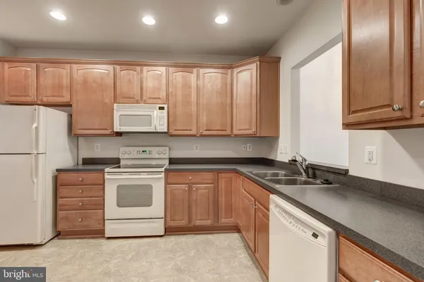 a kitchen with granite countertop cabinets appliances and a sink