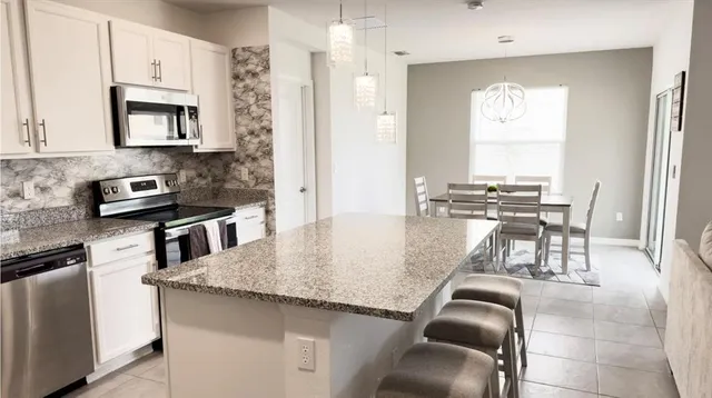 a kitchen with kitchen island granite countertop a table chairs sink and cabinets