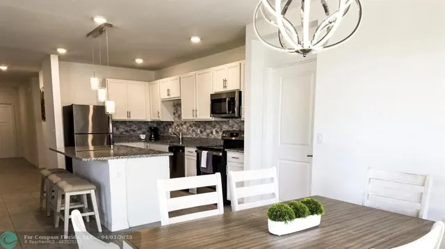 a kitchen with stainless steel appliances kitchen island granite countertop a refrigerator and microwave