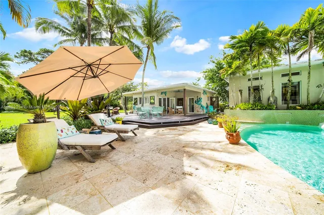 a view of a swimming pool with a table and chairs under an umbrella
