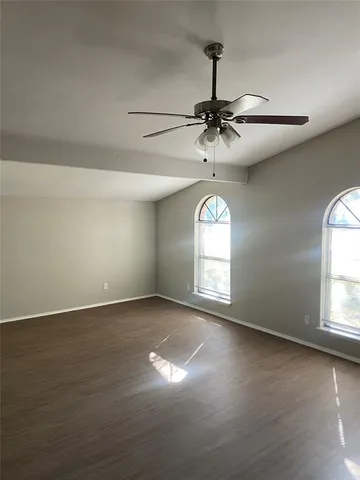 an empty room with a chandelier fan and windows