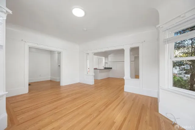 a view of empty room with wooden floor and windows