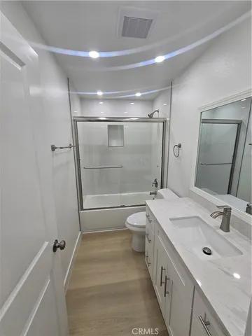a bathroom with a double vanity sink toilet mirror and shower