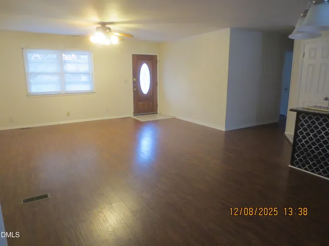 an empty room with wooden floor cabinet and windows