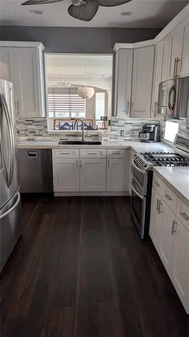 a kitchen with stainless steel appliances a sink dishwasher a stove a refrigerator and cabinets with wooden floor