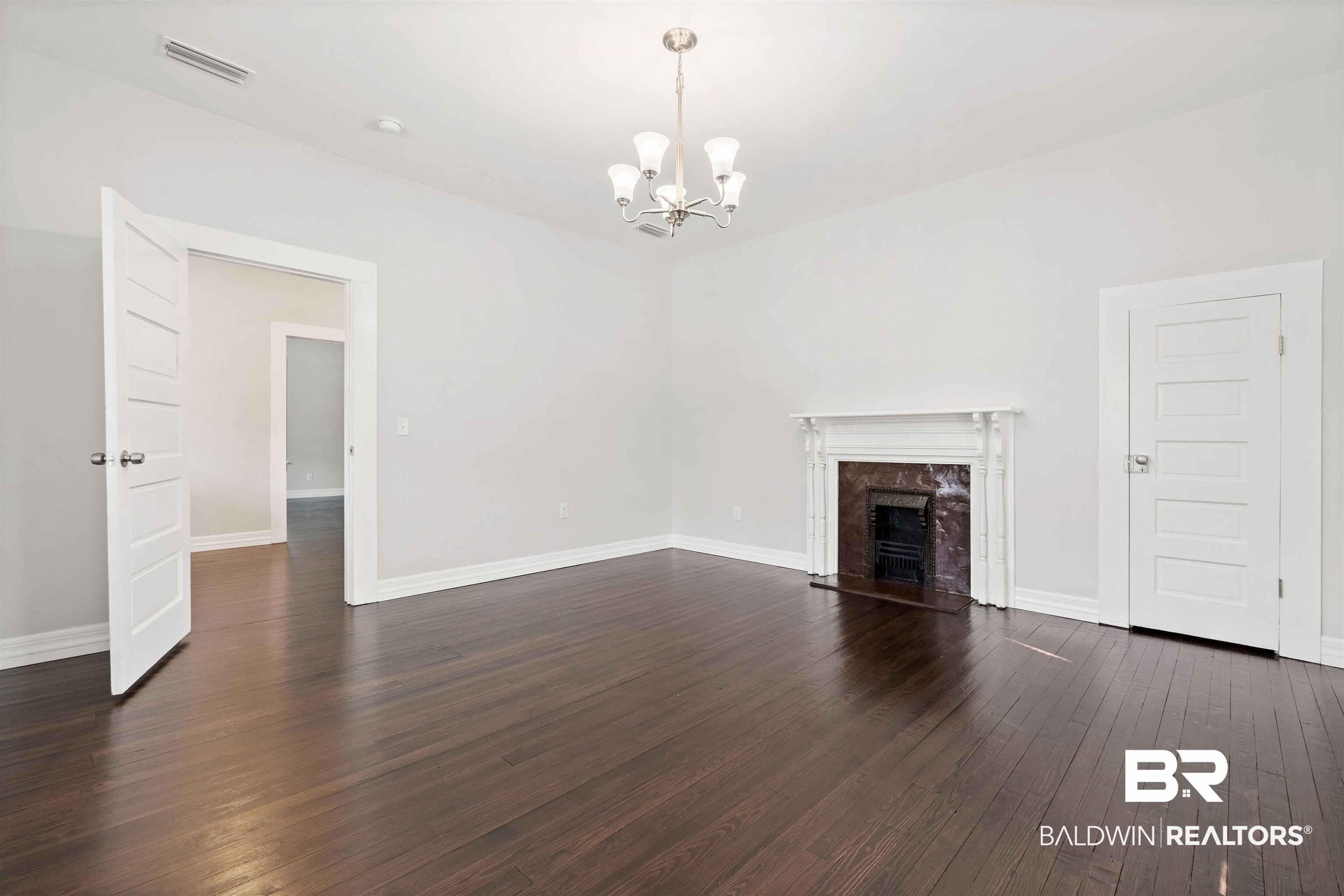 407 East 2nd Street Bay Minette, AL 36507 - Photo 29 of 40 Unfurnished living room with dark wood-style floors, a chandelier, and a fireplace