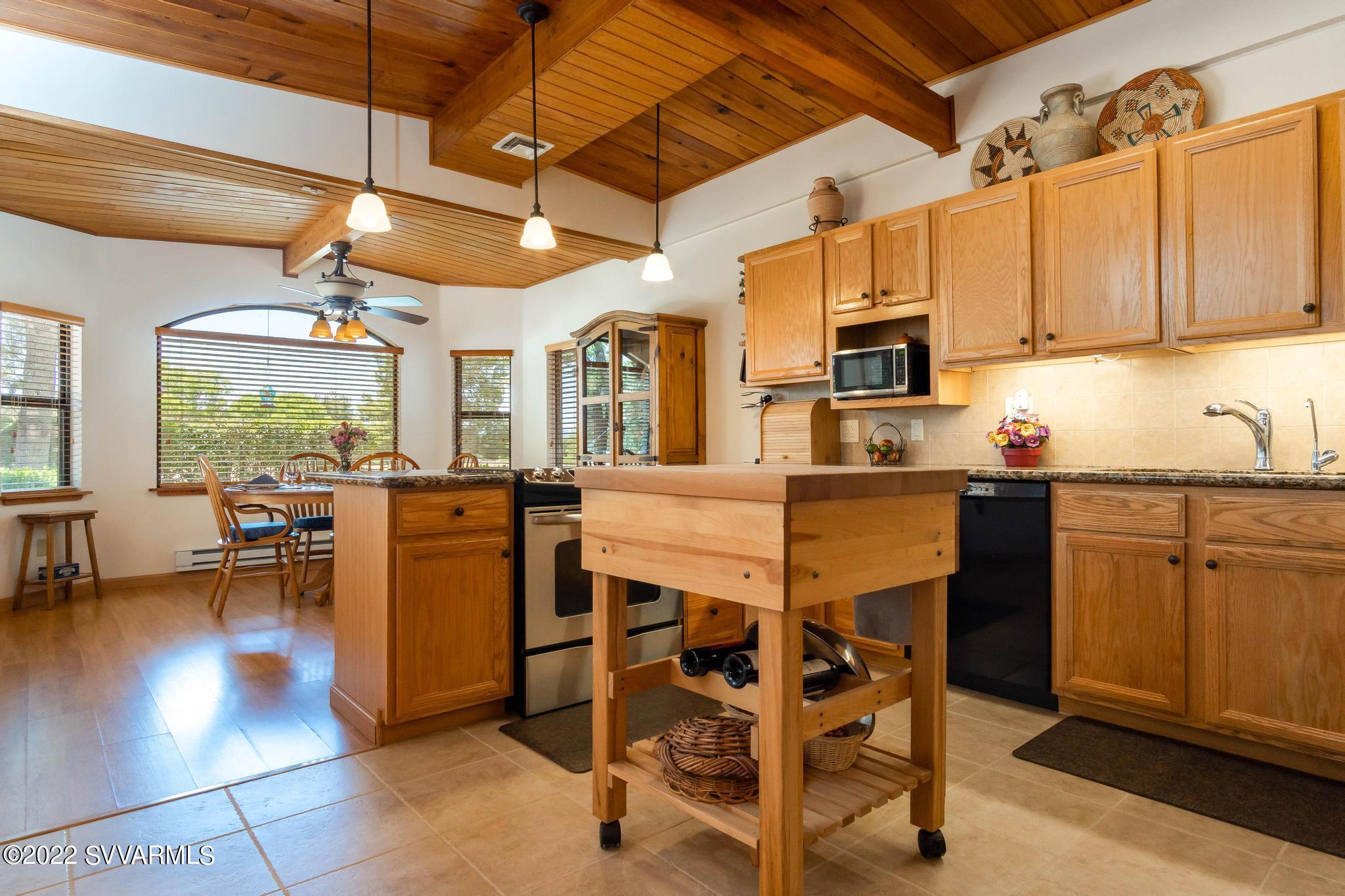 3685 East Rimrock Drive Rimrock, AZ 86335 - Photo 13 of 47 a kitchen with stainless steel appliances granite countertop a stove a sink dishwasher a dining table and chairs with wooden floor