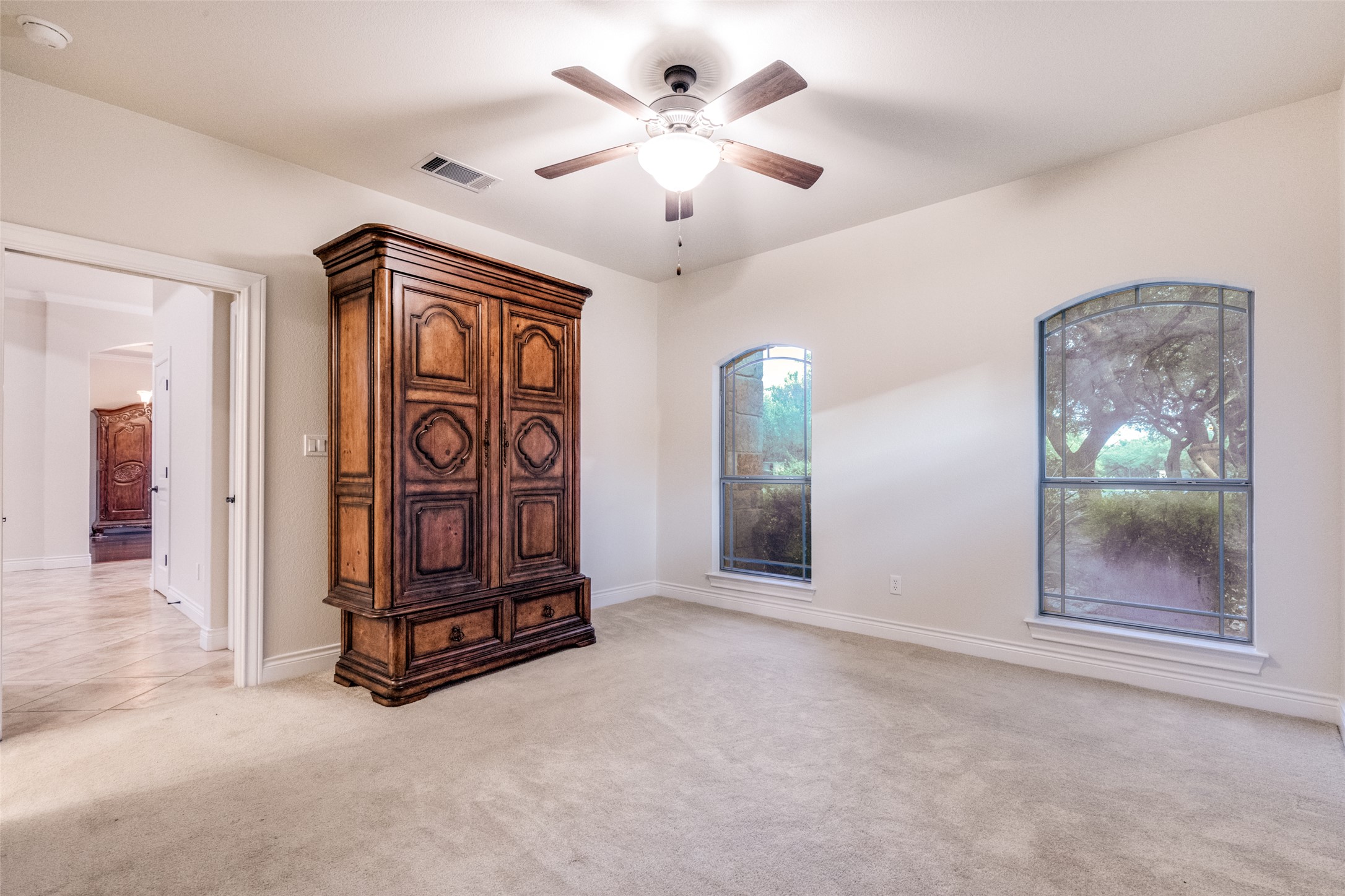 101 Copper Leaf Court Georgetown, TX 78633 - Photo 17 of 31 Arched windows with decorative muntins, neutral carpet flooring, and a ceiling fan with integrated lighting