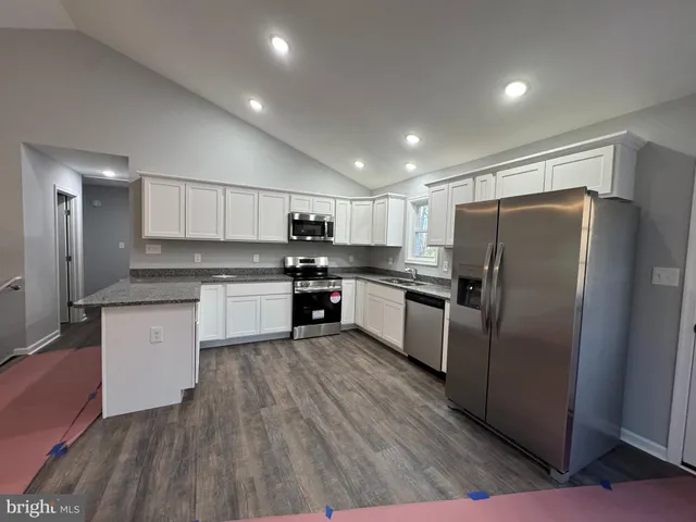 a kitchen with a refrigerator a sink and dishwasher with wooden floor