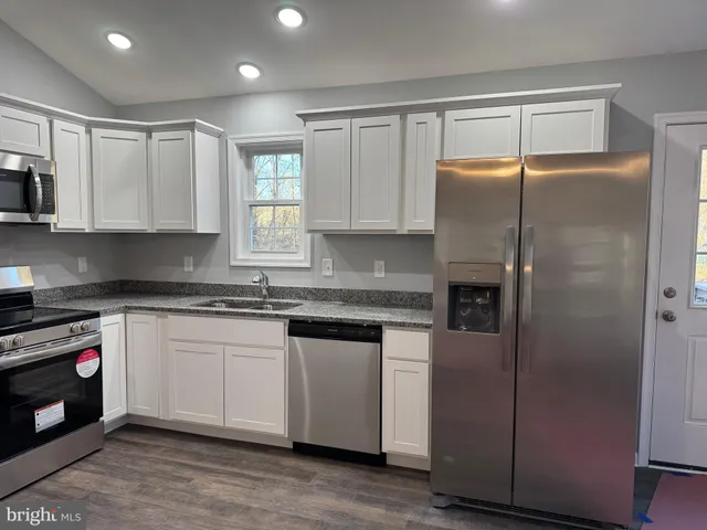 a kitchen with granite countertop a refrigerator and a sink
