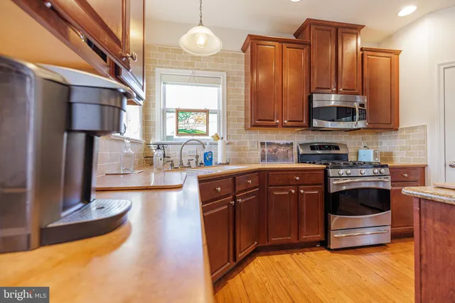 a kitchen with stainless steel appliances granite countertop a stove a sink and a microwave