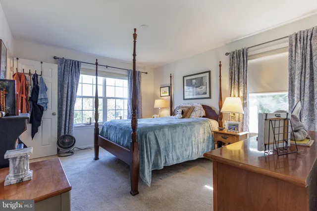 a bedroom with a bed a bookshelf and a window