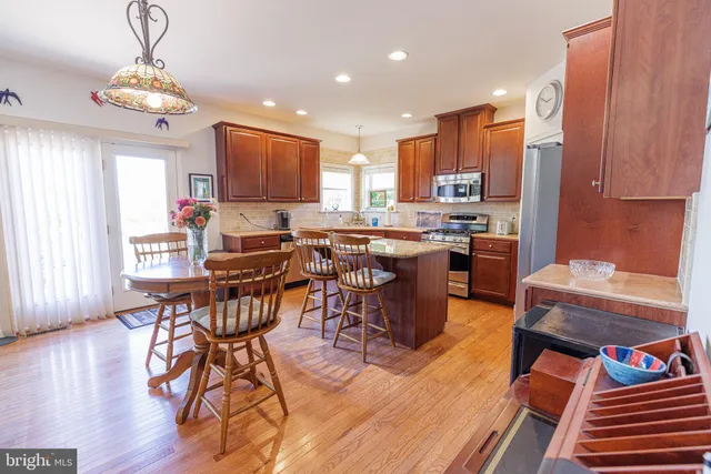 a open dining room with stainless steel appliances a dining table and chairs with wooden floor