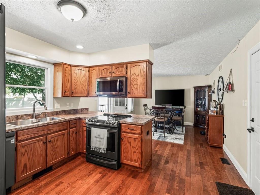 27 Spring Valley Street Slovan, PA 15078 - Photo 9 of 30 a kitchen with stainless steel appliances granite countertop wooden floors a stove top oven a sink dishwasher a dining table and chairs with wooden floor