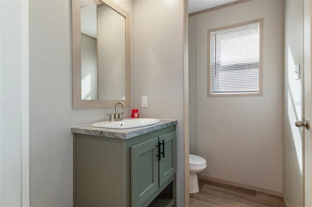 a bathroom with a granite countertop toilet a sink and a window