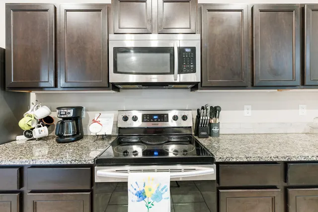 a kitchen with granite countertop a stove microwave and refrigerator