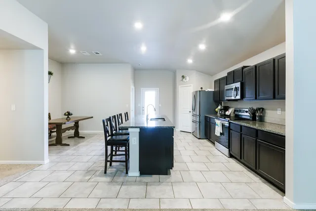 a kitchen with stainless steel appliances granite countertop a stove a sink a microwave and a refrigerator